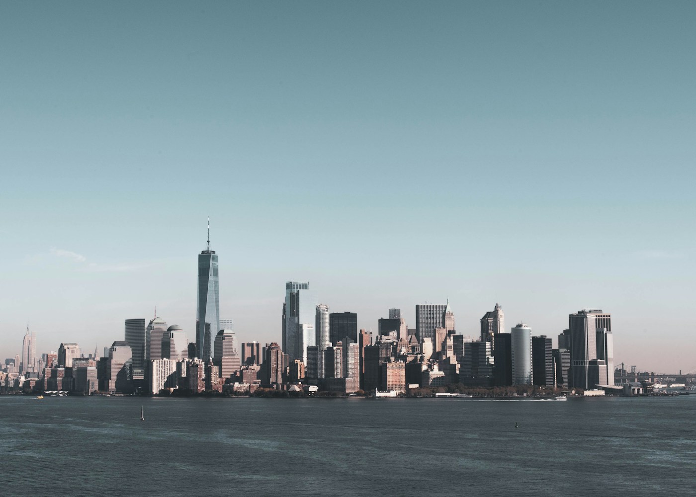 Lower Manhattan skyline across the water beneath a blue sky