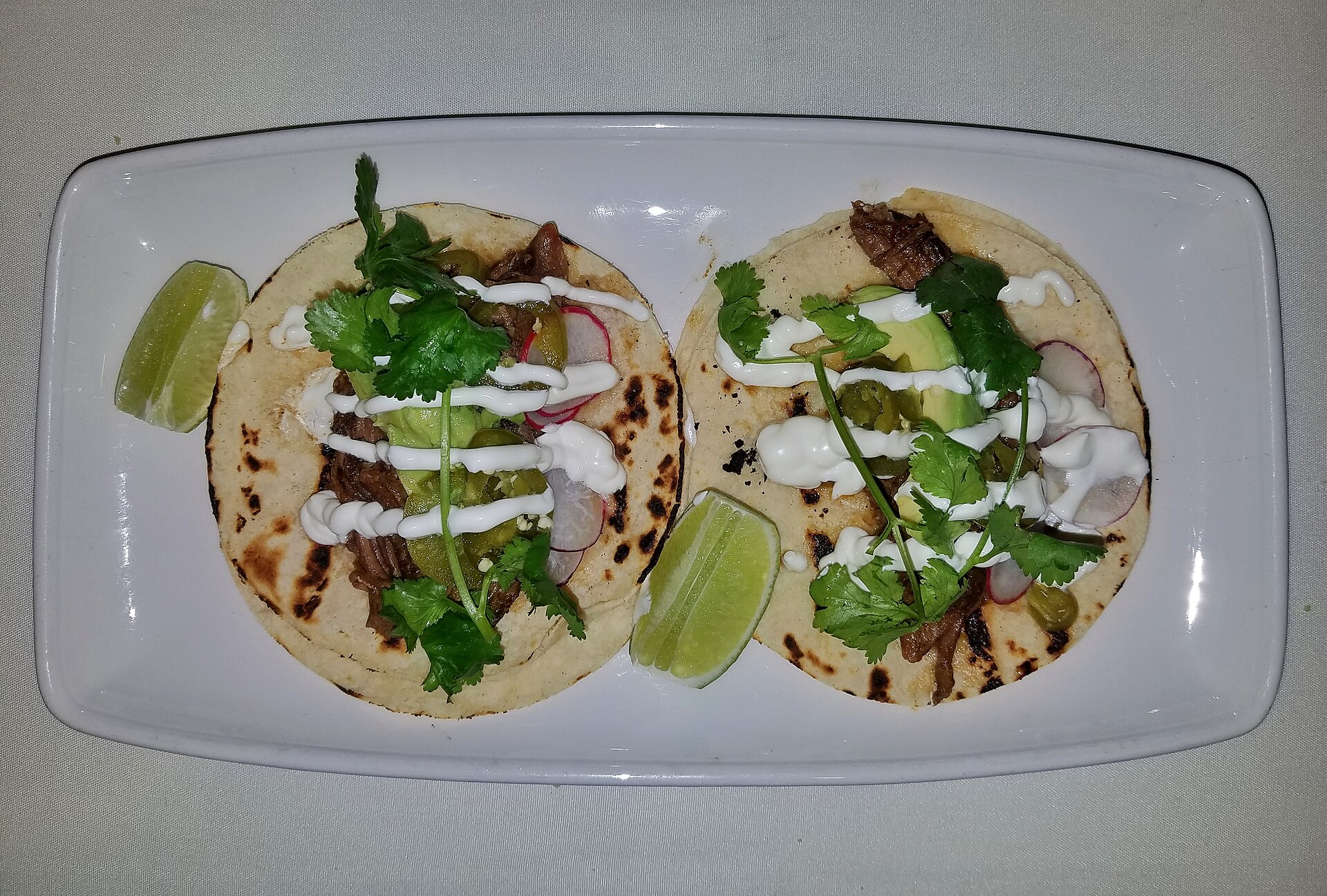 Three tacos topped with cilantro and lime
